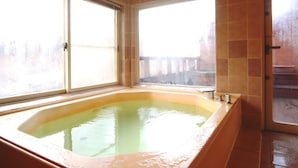 Ein Badezimmer mit einer großen Badewanne, zwei Fenstern und einem gefliesten Boden.