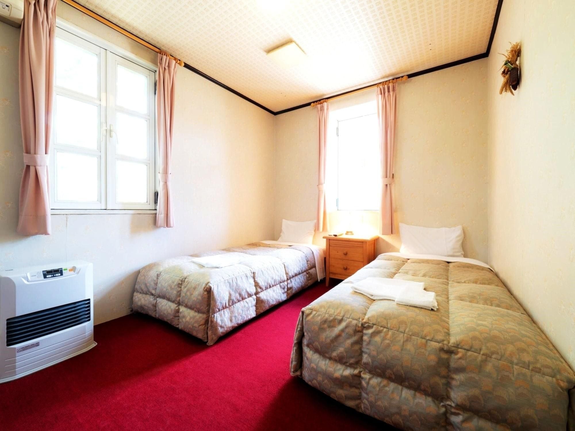Une chambre avec deux lits, un radiateur et une fenêtre avec des rideaux.