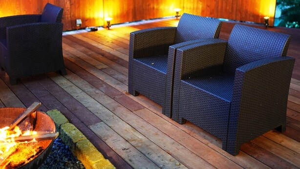 Eine Holzterrasse mit Korbmöbeln und einem Feuerkorb.
