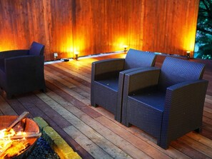 Un patio in legno con mobili in vimini e un braciere.