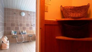 Un baño con ducha, un estante de madera con cestas y piso de azulejos.