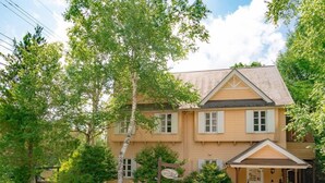 Un bâtiment à deux étages, à la façade beige, doté d’un toit à pignon et d’un porche avec un auvent.