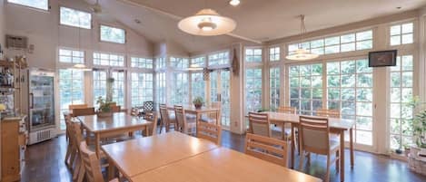 A spacious dining area with large windows and wooden furniture.