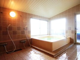 Un baño con una bañera grande, dos cabezales de ducha y un ventanal que proporciona luz natural.