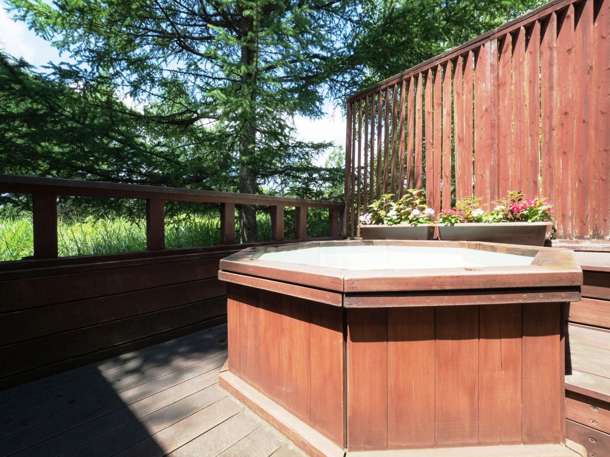 A wooden deck with a hot tub and planters.