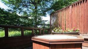 Une terrasse en bois avec un jacuzzi et des jardinières.