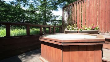 A wooden deck with a hot tub and planters.