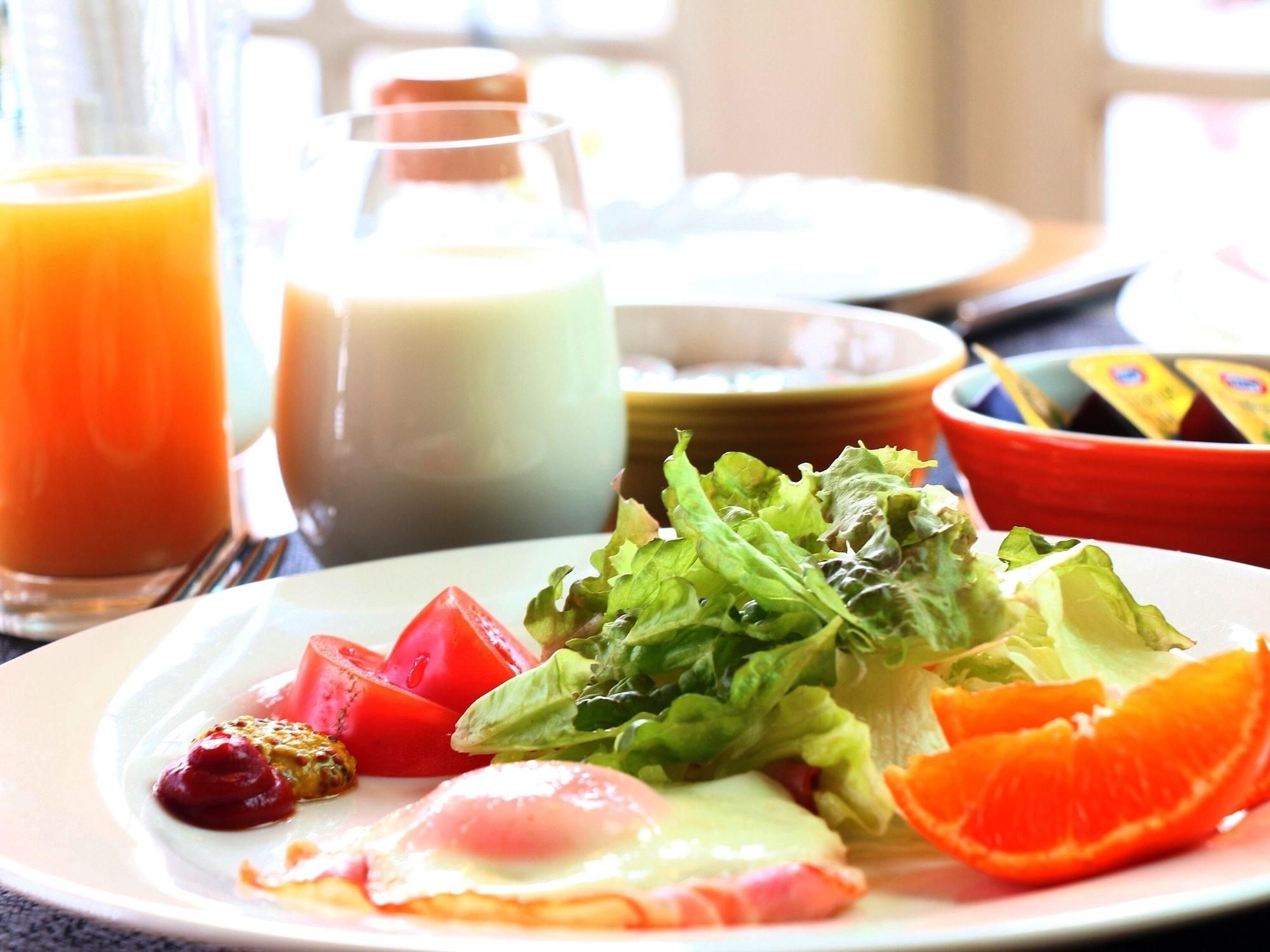A breakfast plate with eggs, tomatoes, lettuce, and orange slices.