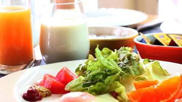 A breakfast plate with eggs, tomatoes, lettuce, and orange slices.