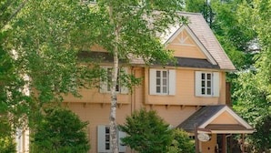Ein zweistöckiges Haus mit Satteldach, einer Veranda und einem kleinen Garten.
