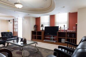 A spacious living room with a large flat-screen TV, comfortable seating, and a decorative lamp. - Capitalia Living Apartments J Verne (Mexico City)