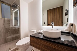 A modern bathroom with a white toilet, a large mirror, a wooden vanity, and a glass shower enclosure. - Capitalia Living Apartments J Verne (Mexico City)