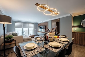 A modern dining area with a glass table set for four, surrounded by dark chairs. - Capitalia Living Apartments J Verne (Mexico City)