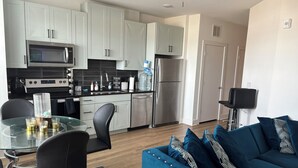 A modern kitchen with white cabinets, stainless steel appliances, and a glass dining table with chairs. - Anna’s City Life Stay (Atlanta)
