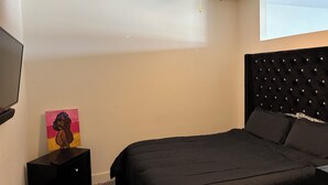 A bedroom with a bed, a ceiling fan, a painting, and a TV on the wall. - Anna’s City Life Stay (Atlanta)