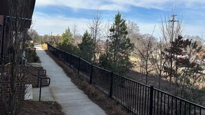 A pathway with a black metal railing, flanked by trees and a building. - Anna’s City Life Stay (Atlanta)