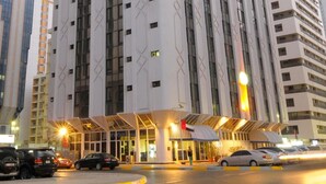 Ein hohes Hotel mit modernem Design, das eine markante Eingangspartie und einen überdachten Bereich mit einem roten Stern zeigt.