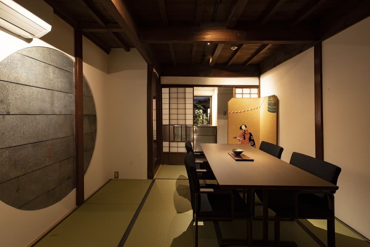 Una habitación japonesa tradicional con suelo de tatami, una mesa baja y puertas correderas.