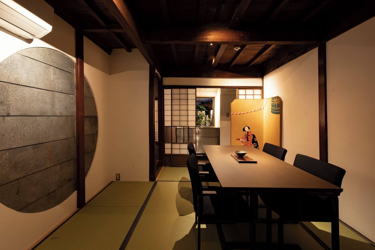 Una habitación japonesa tradicional con suelo de tatami, una mesa baja y puertas correderas.