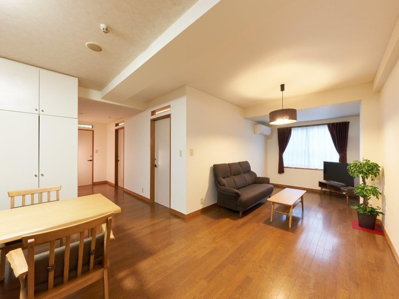 A living room with a sofa, TV, and a dining table.