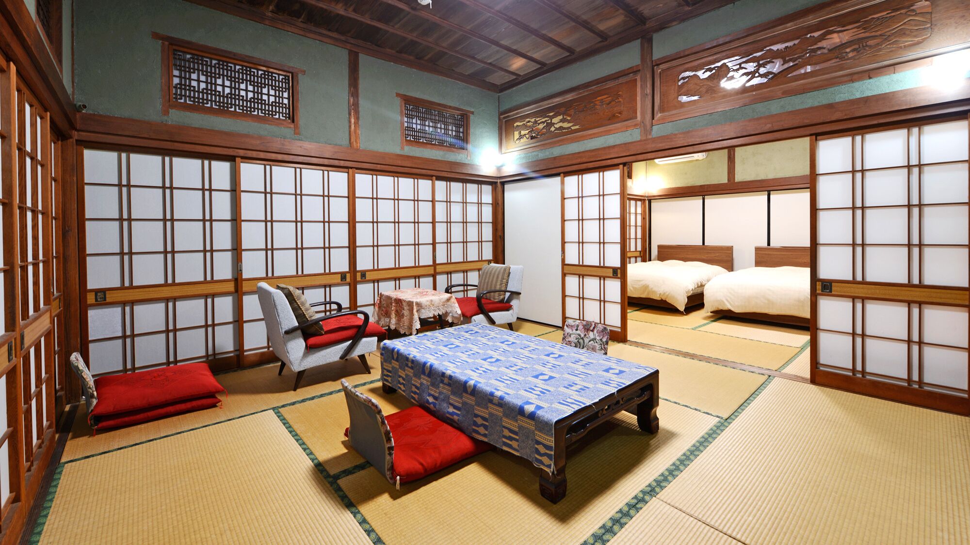Una habitación japonesa tradicional con suelo de tatami, una mesa baja, un sofá y una cama.