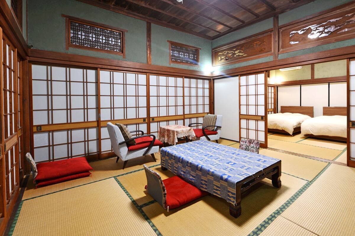 Una habitación japonesa tradicional con suelo de tatami, una mesa baja, un sofá y una cama.
