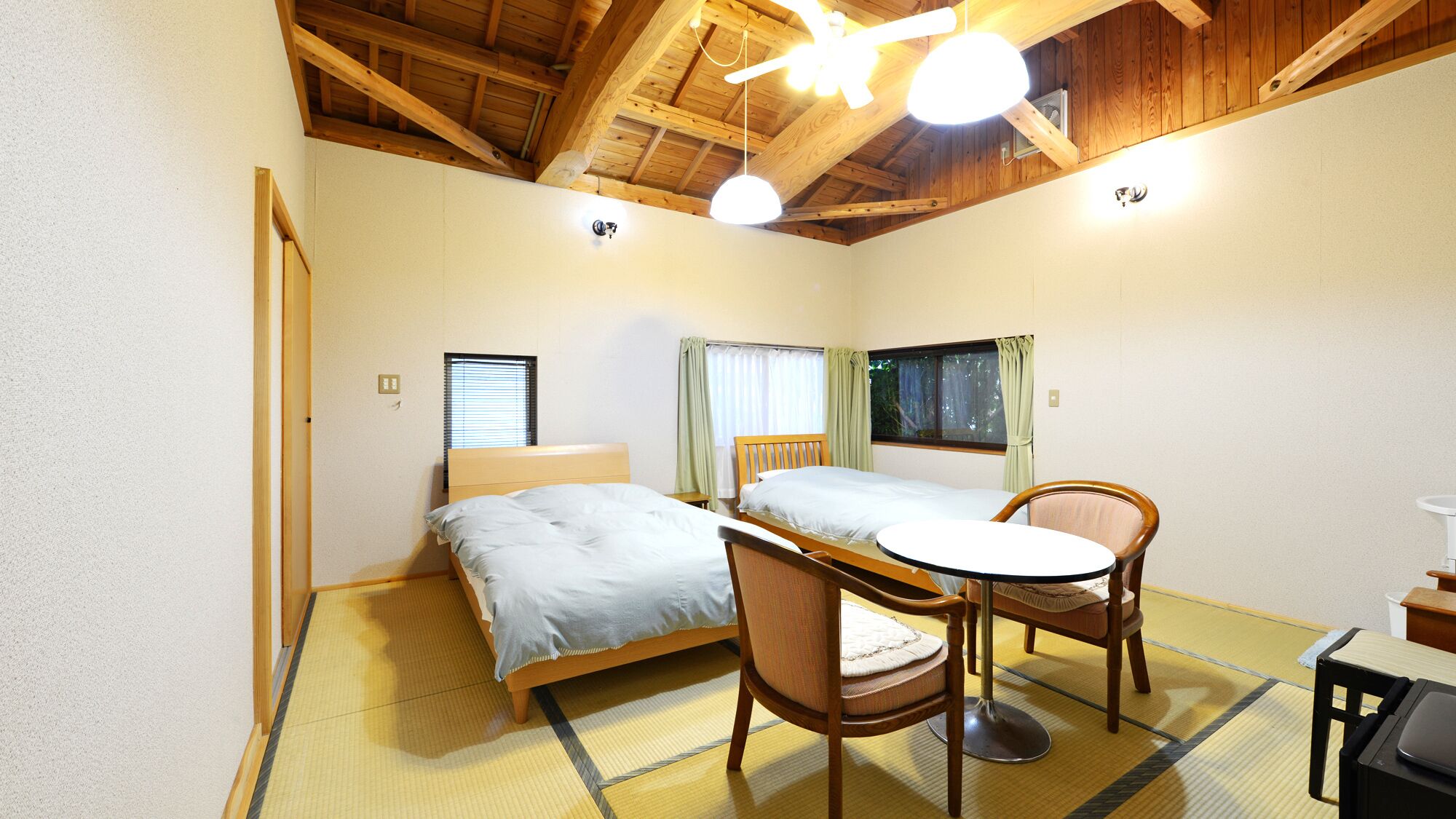 Una habitación con dos camas, una mesita y sillas.