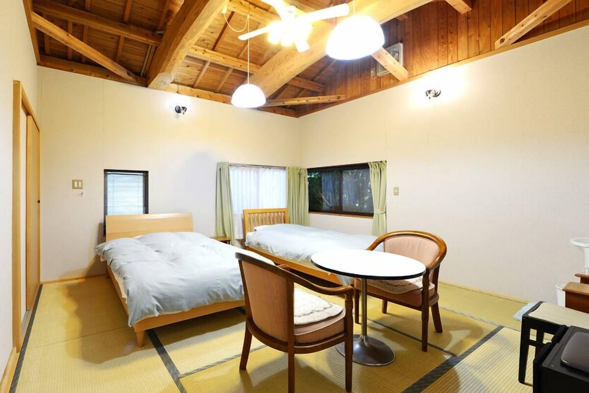 Una habitación con dos camas, una mesita redonda y una silla.
