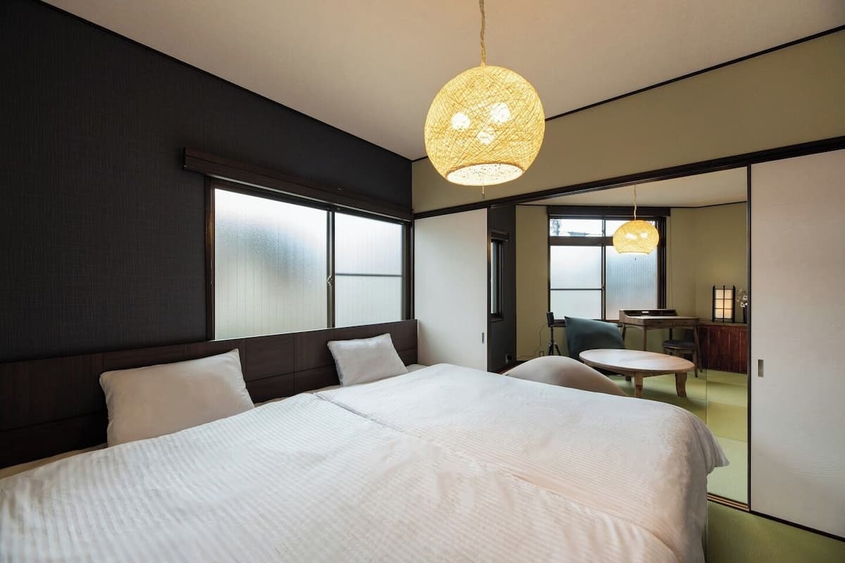 A hotel room with a large bed, a dining area, and a view through a sliding door.