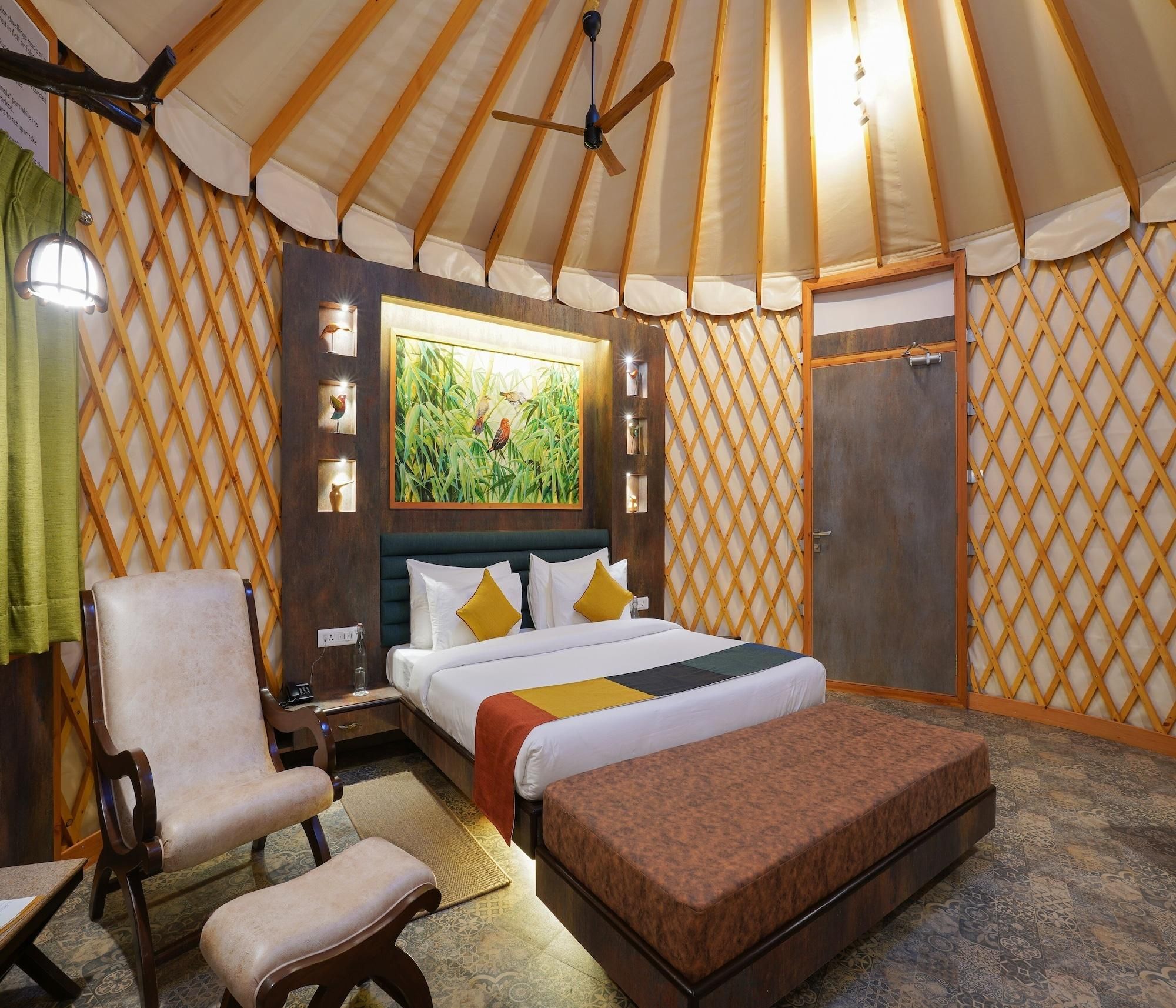 A room with a bed, a chair, a bench, a wooden wardrobe, and a painting on the wall.