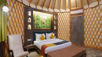 Una habitación con una cama, una silla, un banco, un armario de madera y un cuadro en la pared.