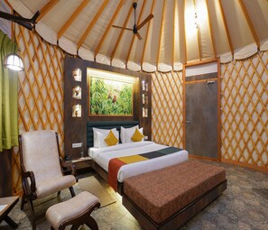 Una habitación con una cama, una silla, un banco, un armario de madera y un cuadro en la pared.