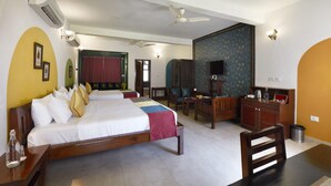 Una habitación de hotel con una cama grande, un escritorio, una silla, un televisor y un armario.