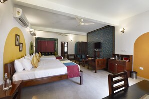 Ein Hotelzimmer mit einem großen Bett, einem Schreibtisch, einem Sessel, einem Fernseher und einem Kleiderschrank.