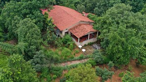 Une maison entourée d’une végétation luxuriante, avec un toit recouvert de tuiles rouges et un patio abrité.