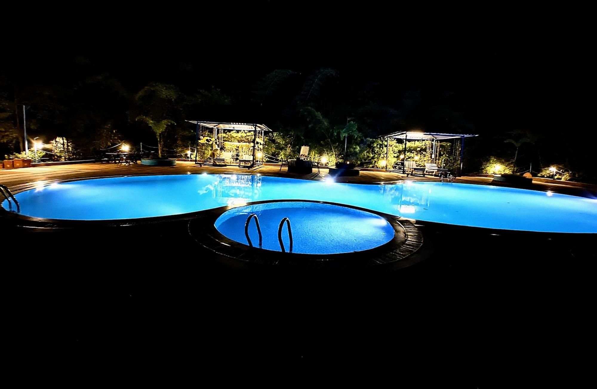 Una piscina con hidromasaje, rodeada de sillas de descanso y una zona cubierta con iluminación.
