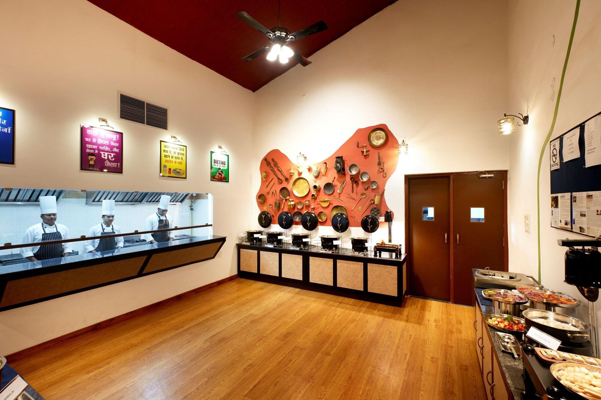 A restaurant with a wooden floor, a wall decorated with kitchen utensils, and a buffet area with various dishes.
