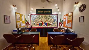 Un salón de conferencias con una mesa central, cuatro sillas, un ventilador de techo y decoración en las paredes.