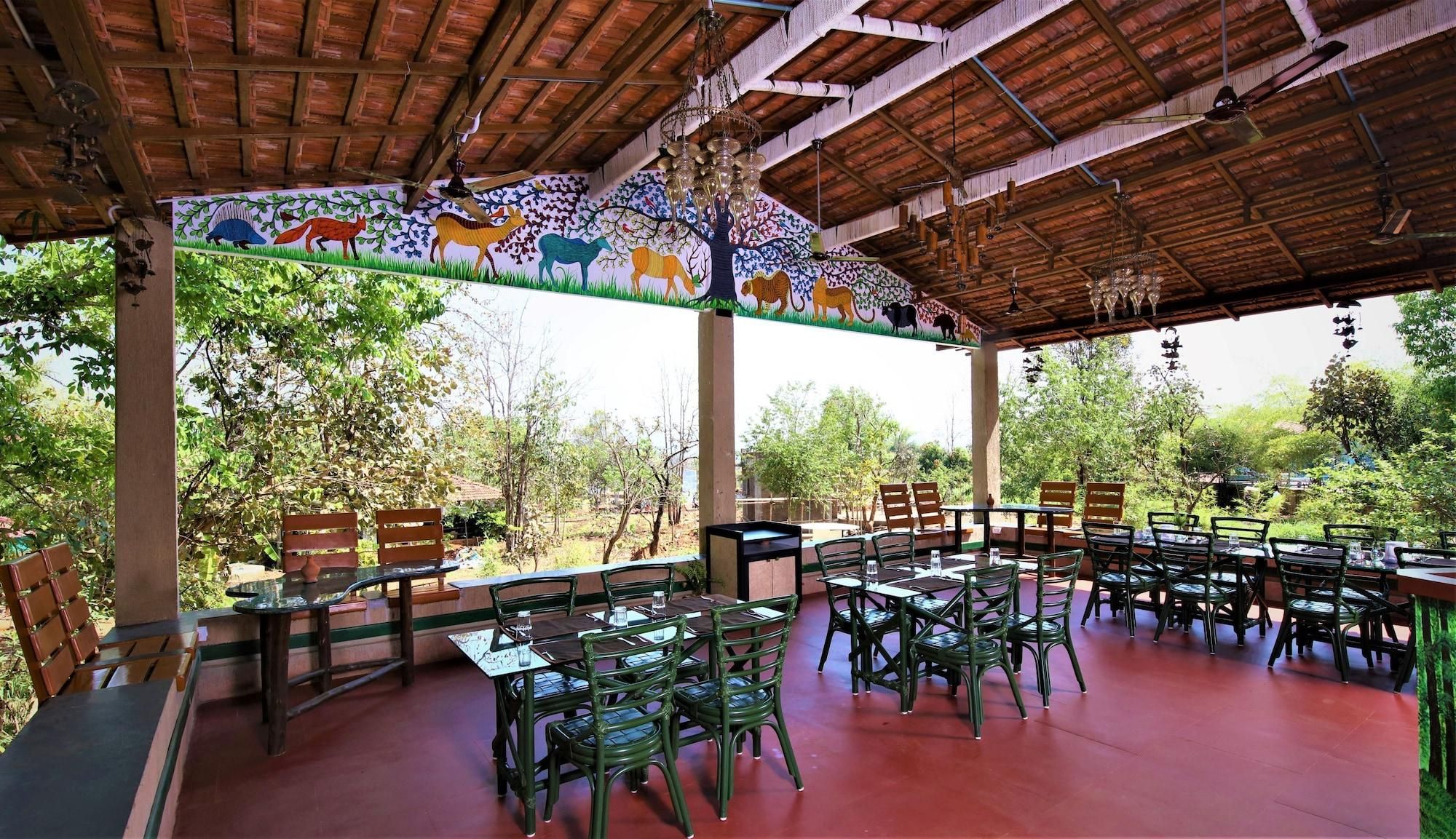 An outdoor dining area with wooden tables and chairs, surrounded by a mural of animals.