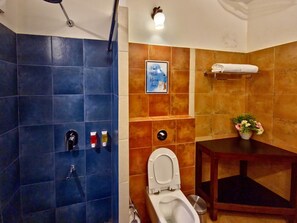 Ein Badezimmer mit Duschbereich, Toilette, Waschbecken und Handtuchhalter.