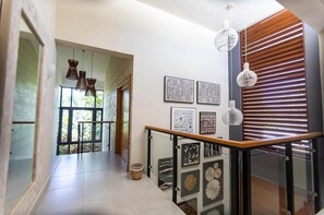 Ein moderner Flur mit Glastrennwand, Kunstwerken an der Wand und einer Holzhakenschrankwand rechts.
