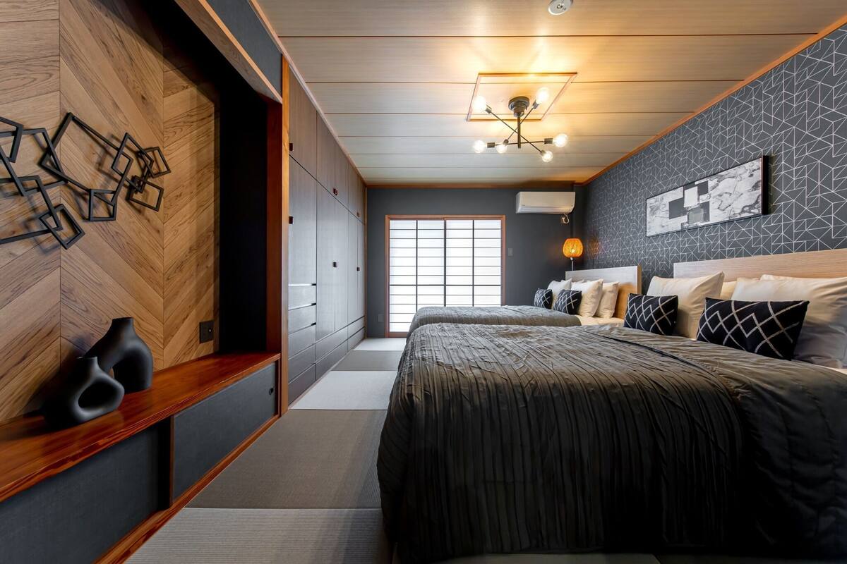 A modern bedroom with a large bed, a wooden wardrobe, and a geometric wall design.