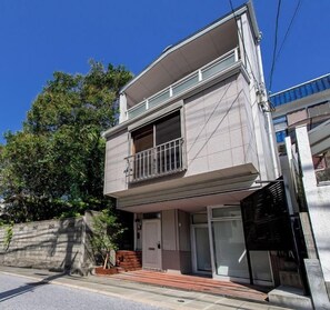 A two-story residential building with a balcony, a visible entrance, and a clear sky. - Oyado Urushi (Nagasaki)