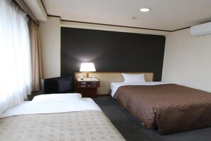 Habitación de hotel con dos camas, un escritorio, una silla, una lámpara y una ventana con cortinas.