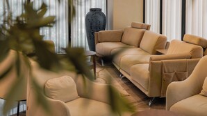 En moderne stue med en beige hjørnesofa, et lille bord og en stor vase.