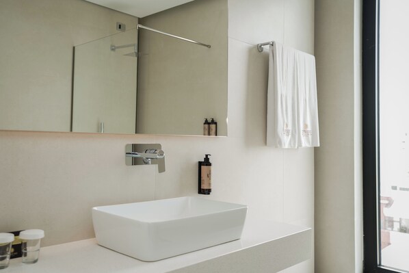 Une salle de bain moderne avec un grand miroir, un lavabo blanc et une serviette suspendue à un porte-serviettes.