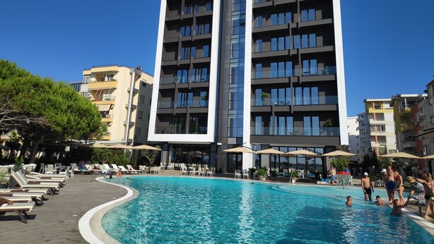 Et moderne hotel med swimmingpool, flere balkoner og udendørs siddeområder.