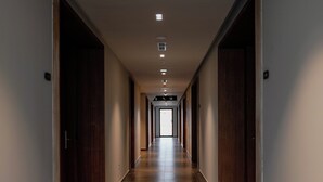 A long, narrow hallway with wooden doors on both sides and a tiled floor. - Supreme Hotel (Golem)