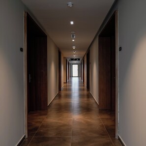 A long, narrow hallway with wooden doors on both sides and a tiled floor. - Supreme Hotel (Golem)