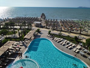 A resort with a large swimming pool, beach area with umbrellas, and lounge chairs. - Supreme Hotel (Golem)